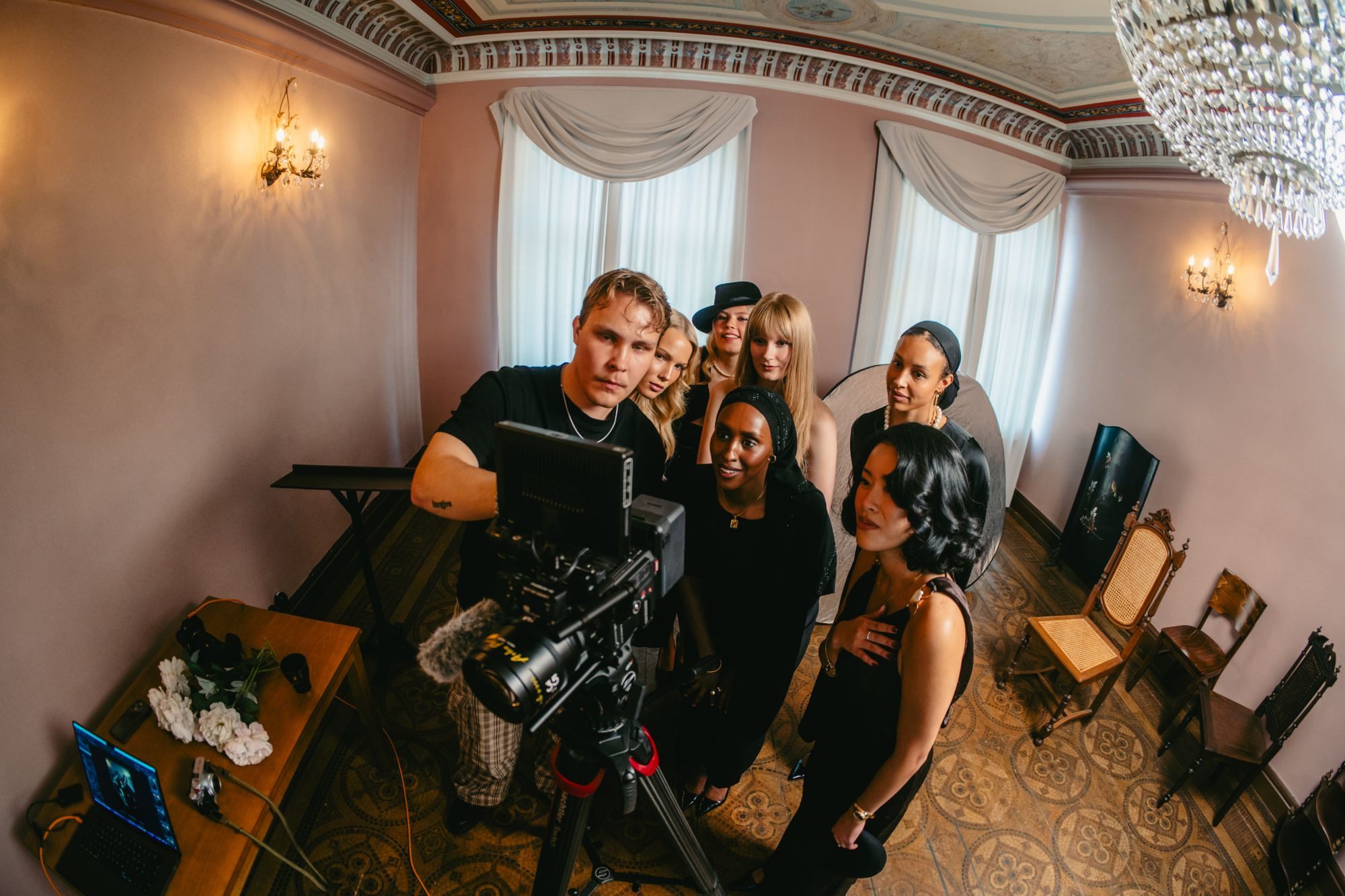 Lucas Ekblad on set, showing a group of models the shot on the camera monitor under a chandelier.