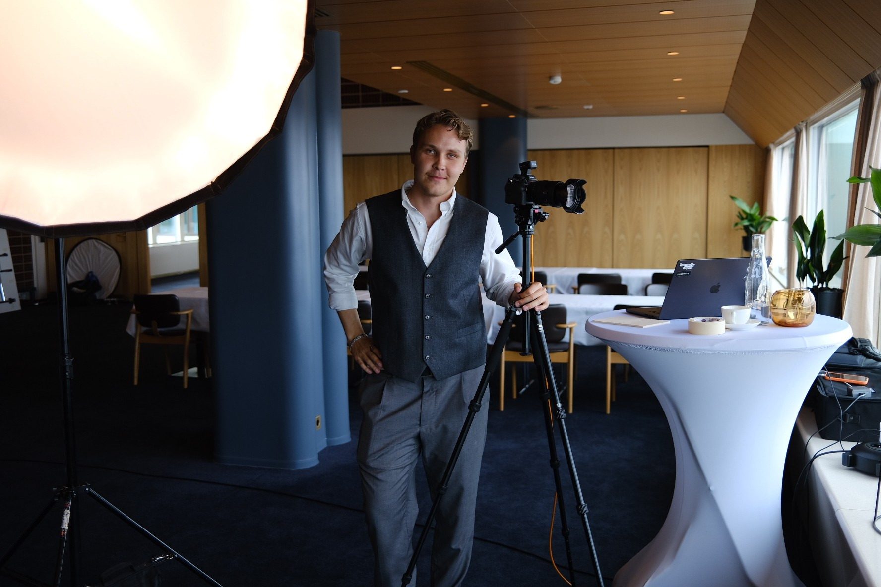 Lucas Ekblad beside a camera on a tripod and a large softbox, set up for portraits in a conference room.