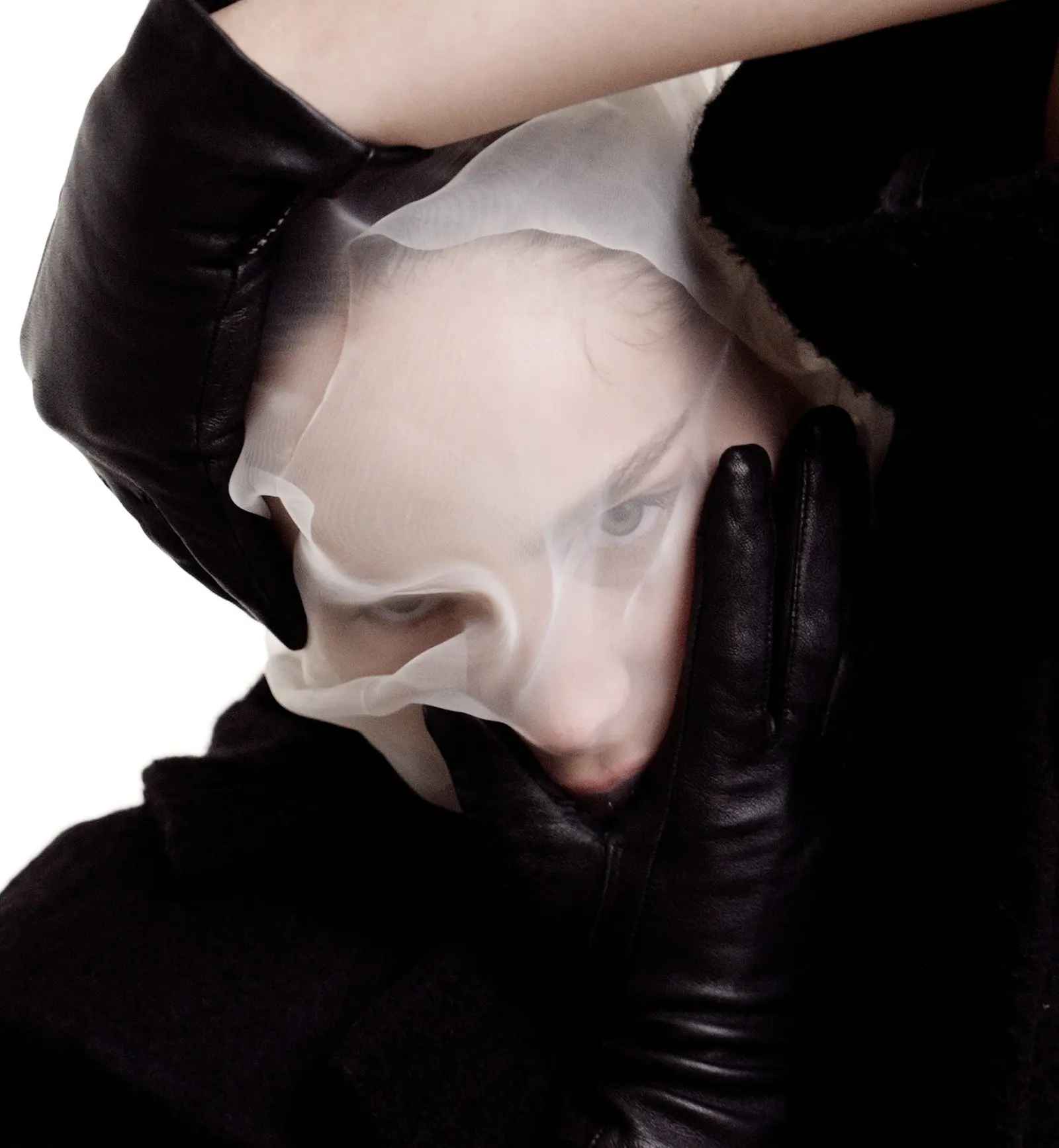 Fashion editorial photography: black on white: A black-on-white fashion editorial: long coats, leather gloves and a sheer…